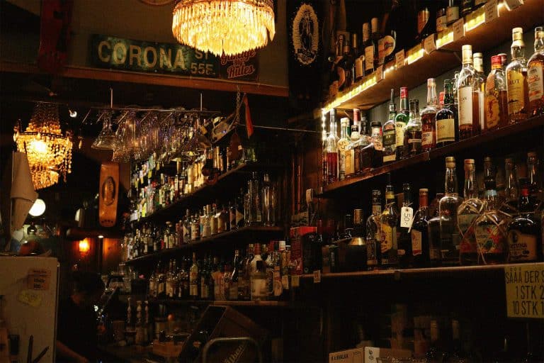 Dimly lit, cozy bar with alcohol bottles on shelves